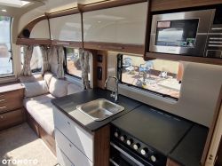 Interior of a modern camper trailer with a kitchenette and seating area.