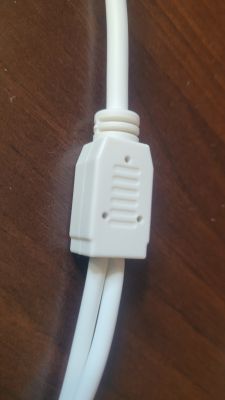 Biały kabel z prostokątnym złączem na drewnianym tle.
