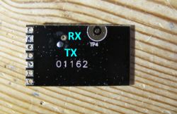 Photo of a small electronic module with RX and TX markings on a black background.