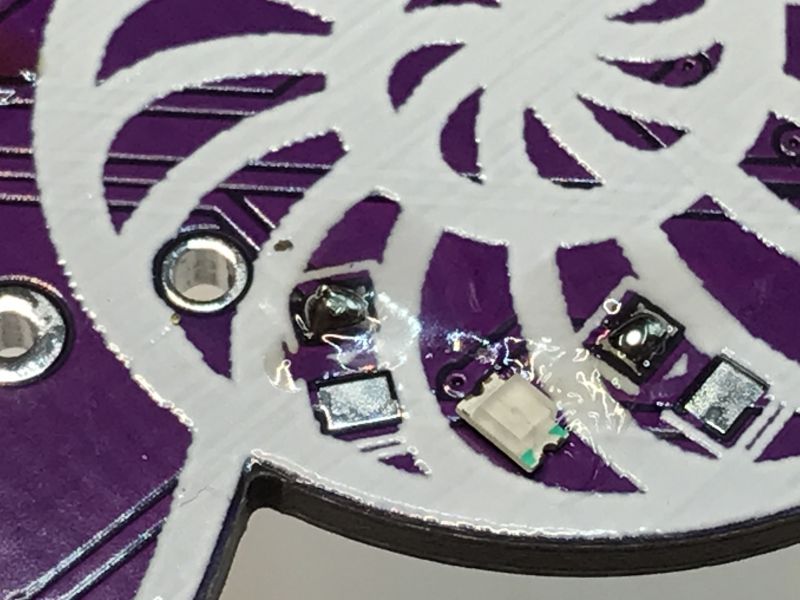 SMD Components Mounted on PCB Close-up of a PCB section with mounted SMD components, including an LED, on a purple and white patterned background.