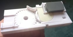 White plastic gear mechanism, 3D printed, designed for narrowing photographic film.