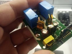 Photo of a circuit board with various electronic components held in hand.