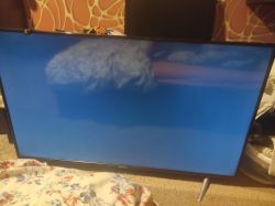 Telewizor wyświetlający jednolite niebieskie tło w pokoju.