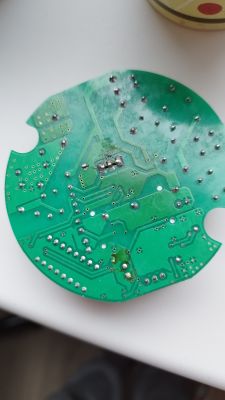Zbliżenie na zieloną płytkę PCB z widocznymi lutami i ścieżkami obwodów.