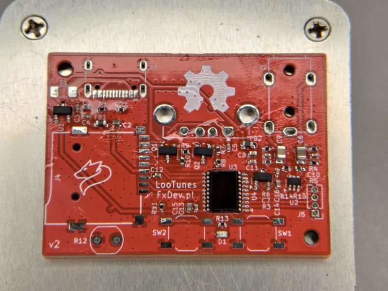 Red LooTunes PCB with microcontroller and SMD components mounted.