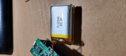 Bateria litowo-polimerowa PL 622640 o pojemności 600 mAh na drewnianym blacie, obok płytki elektronicznej lampki rowerowej.