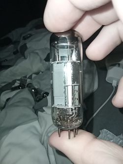 Szklana lampa elektronowa trzymana w palcach na tle łóżka