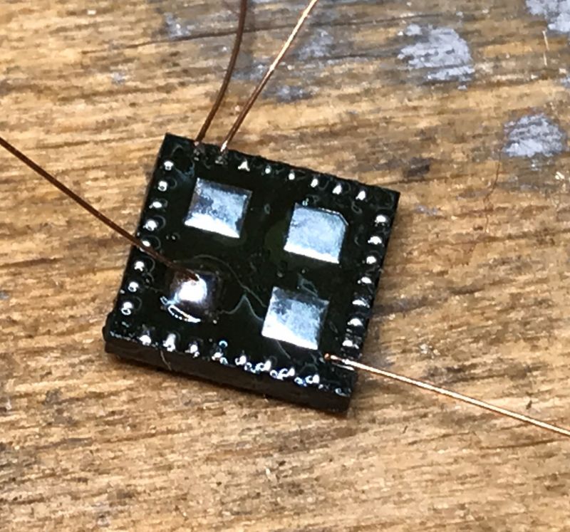 Electronic Component with Wires Square electronic component with soldered copper wires on a wooden surface.
