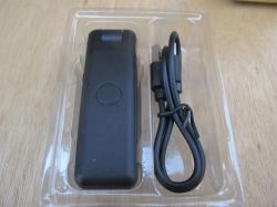 Bluetooth remote and USB cable in packaging Black Bluetooth remote and USB cable in plastic packaging.