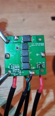 Zielona płytka drukowana z różnymi komponentami elektronicznymi i podłączonymi przewodami.
