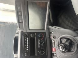 Widok na konsolę środkową w samochodzie z zamontowanym radiem i ekranem dotykowym.