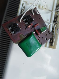 Wnętrze radzieckiej ładowarki akumulatorków AA z widocznymi elementami elektronicznymi, w tym pękniętym rezystorem.