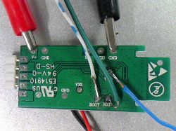 Green circuit board with connected wires on a table.