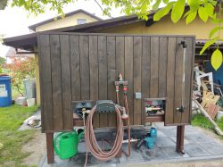 Wooden structure in a garden with a water system and gardening tools.