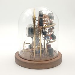 Zegar Nixie w szklanej obudowie z widocznymi elementami elektronicznymi na drewnianej podstawie.