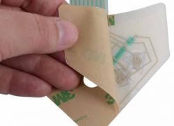 Osoba trzyma kawałek taśmy dwustronnej z przymocowaną płytką obwodów wentylatora.