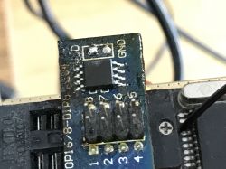 Close-up of an integrated circuit connected to a programmer with labeled pins and wires