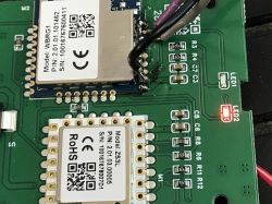 Circuit board with two electronic modules and a lit red LED.