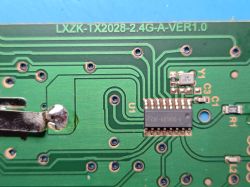 Close-up of a green PCB with an IC, traces, and the printed text “LXZK-TX2028-2.4G-A-VER1.0”
