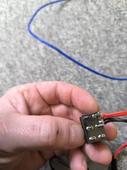 Ręka trzymająca element elektroniczny z podłączonymi przewodami.