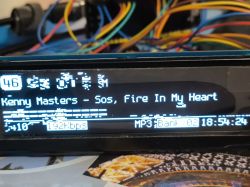Car radio display showing strange symbols and the song title Kenny Masters - SOS, Fire In My Heart.