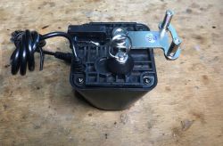Jinvoo SM-AW713 WiFi Valve Overlay View of the valve overlay with a black housing and mounting mechanism on a wooden surface.