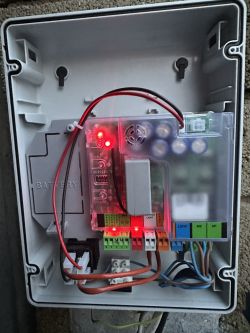 Centrala FAAC e024s z podłączonymi przewodami i świecącymi diodami.