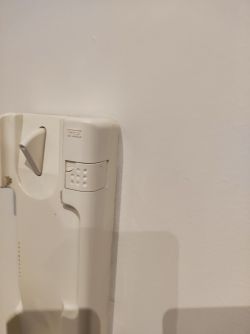 White intercom mounted on the wall with buttons and a lever.