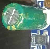 Capacitor and Integrated Circuit on a Circuit Board Close-up of a green cylindrical capacitor and a circuit board with a visible integrated circuit.