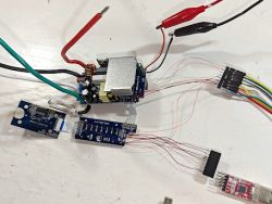 Disassembled electronic circuit board with connected wires on a white background.