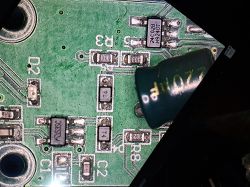 Zbliżenie na uszkodzoną płytkę PCB z zalanym kondensatorem i oznaczeniami elementów