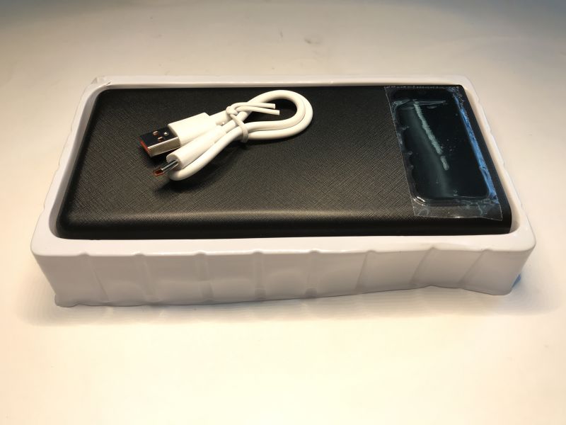 Black power bank in a white tray with a coiled white USB cable on top
