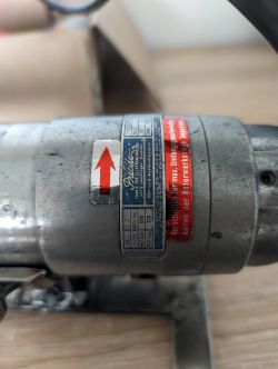 Zbliżenie na tabliczkę znamionową starego silnika elektrycznego zamontowanego we frezarce.