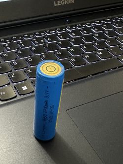 Akumulator 18650 z nietypowymi biegunami na klawiaturze laptopa.