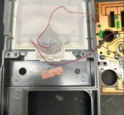 Wnętrze miernika z cienkim czerwonym przewodem i płytką PCB po prawej
