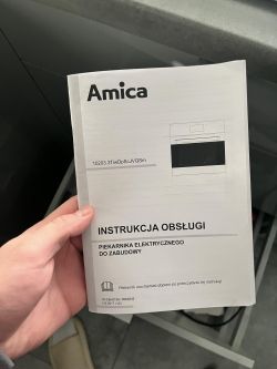Osoba trzymająca instrukcję obsługi piekarnika Amica EB9333BA+ IN.