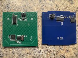 RFID modules on green and blue printed circuit boards Two RFID PCB modules on a tabletop, one green and one blue, with mounted electronic components.