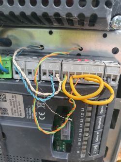 Zbliżenie na panel centrali z podłączonymi przewodami różnokolorowymi w portach oznaczonych numerami.