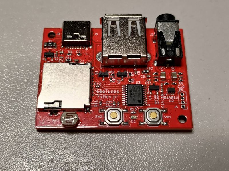 Close-up of red LooTunes PCB with USB ports, mini-jack, and control buttons