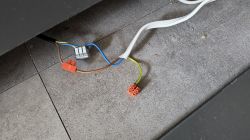 Przewody elektryczne połączone kostkami typu Wago na tle podłogi z płytek