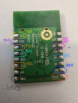 Green PCB module with solder pads, printed pin labels, and handwritten colored markings for UART and power