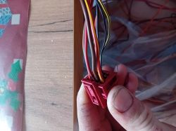 Zbliżenie na czerwoną plastikową wtyczkę z wieloma przewodami o różnych kolorach.