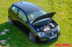 Czarny VW Polo 9N z otwartą maską, ukazujący silnik R32, stojący na zielonej trawie.