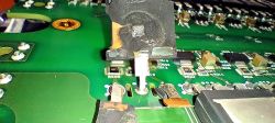 Zbliżenie na uszkodzony tranzystor mocy na zielonym PCB modułu ICCU
