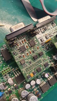 Zbliżenie na płytkę drukowaną z zamontowanymi komponentami elektronicznymi, w tym kondensatorami, złączami i potencjometrami.