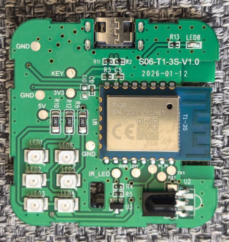 Green PCB with micro‑USB port, T1‑3S module, multiple LEDs, and an IR sensor on a woven fabric background