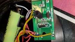 Płytka drukowana z elementami elektronicznymi i przewodami w lampie solarnej ogrodowej z widocznym akumulatorem.