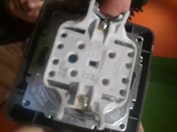 Zbliżenie na tył włącznika elektrycznego z widocznymi zaciskami.