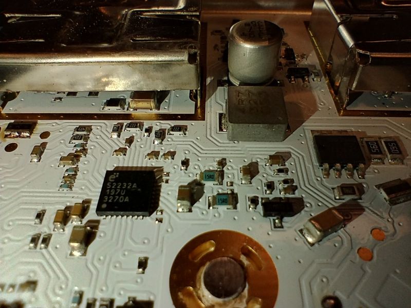 Nahaufnahme einer Leiterplatte mit elektronischen Bauteilen wie Kondensatoren, IC und Spule.