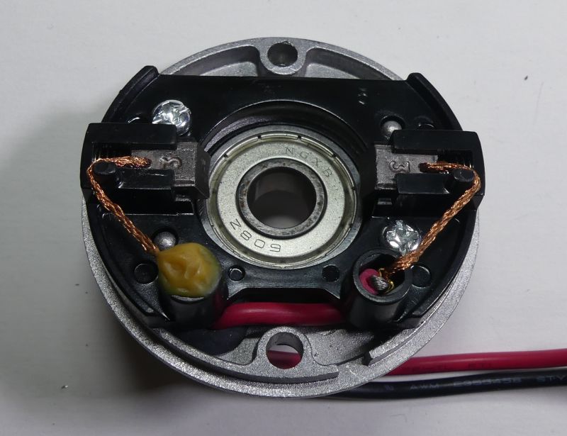 Silnik elektryczny z widocznymi szczotkami i łożyskiem.